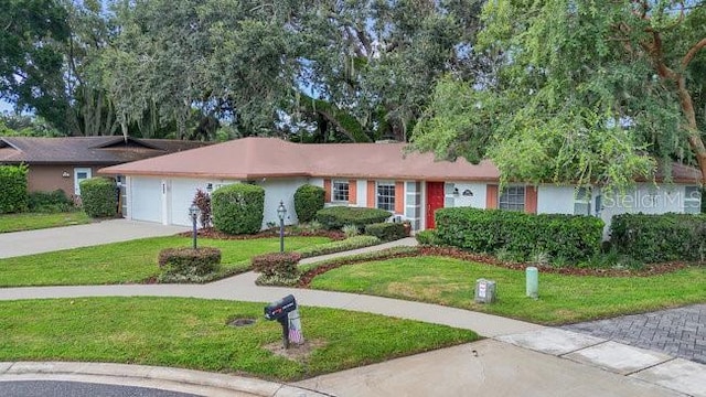 ranch-style house featuring concrete driveway, an attached garage, and a front lawn