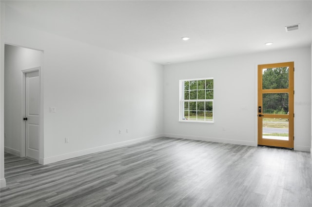 unfurnished room featuring light wood finished floors, plenty of natural light, visible vents, and baseboards