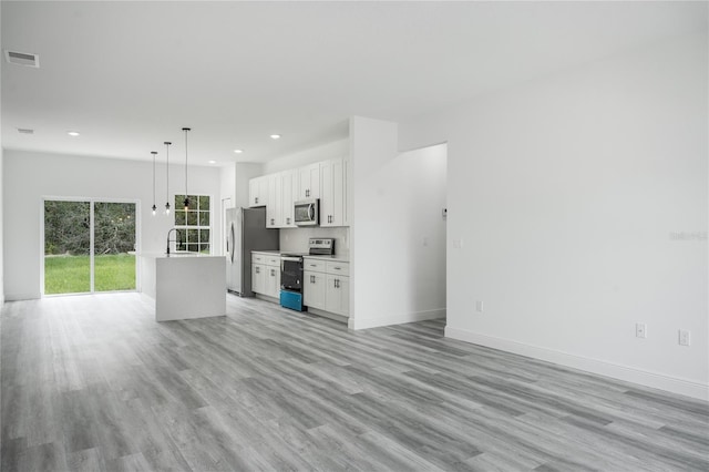 unfurnished living room with baseboards, visible vents, light wood-style floors, a sink, and recessed lighting