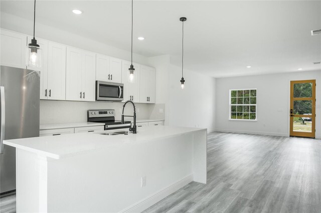 kitchen featuring white cabinets, light wood-type flooring, appliances with stainless steel finishes, and an island with sink