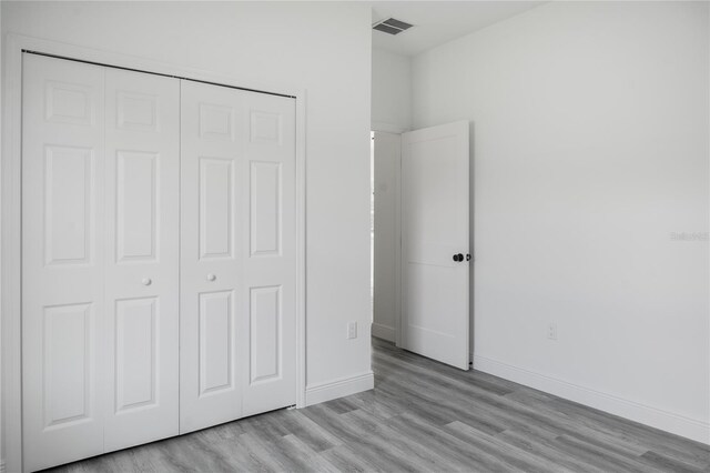 unfurnished bedroom with light hardwood / wood-style flooring and a closet