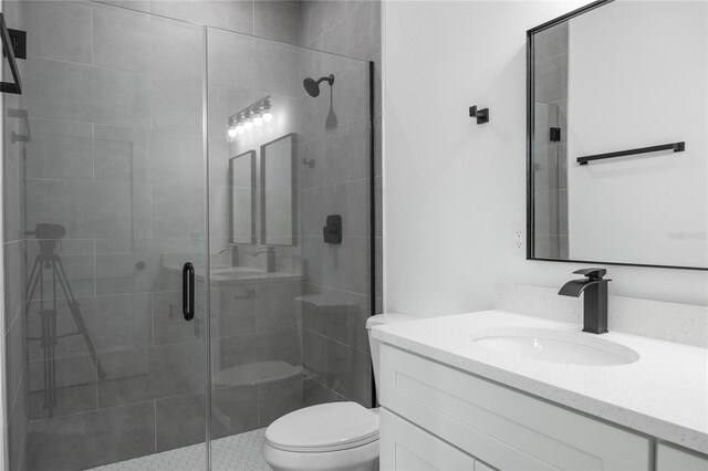 bathroom featuring a shower with door, vanity, and toilet