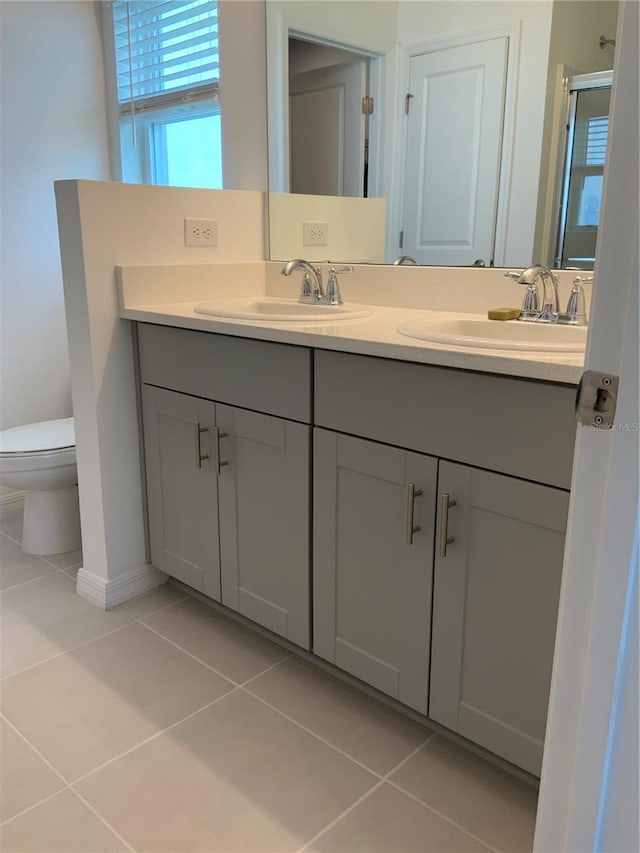 5639 Costa Blanca Way, Davenport, FL 33897 - bathroom featuring tile patterned flooring, double vanity, toilet, a shower with door, and baseboards
