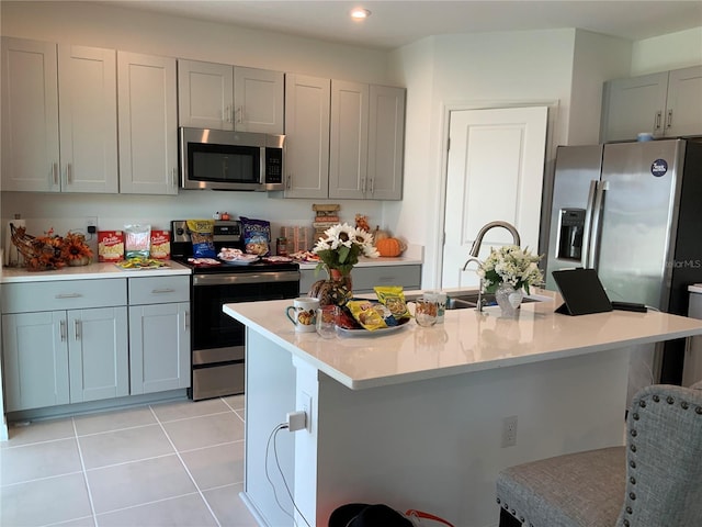 5639 Costa Blanca Way, Davenport, FL 33897 - kitchen featuring stainless steel appliances, gray cabinetry, a kitchen bar, light tile patterned flooring, and light countertops