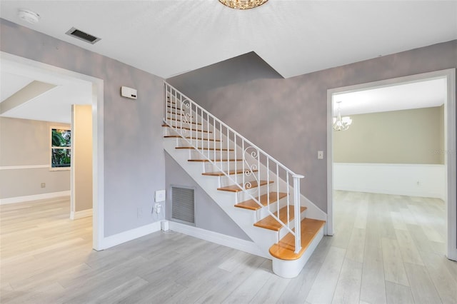 stairway with hardwood / wood-style flooring and an inviting chandelier