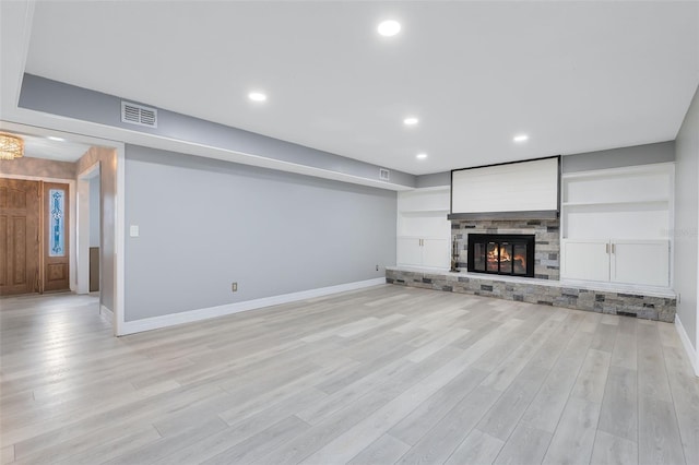 unfurnished living room with light hardwood / wood-style flooring and a stone fireplace