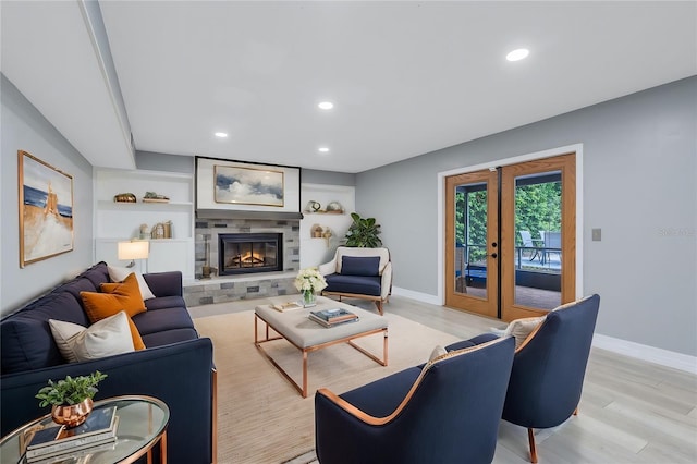 living room featuring french doors, light hardwood / wood-style flooring, and a stone fireplace