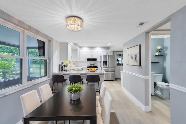 dining space with light wood-type flooring, sink, and a notable chandelier