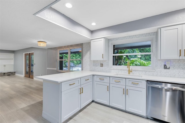 kitchen with light wood-type flooring, a healthy amount of sunlight, sink, and stainless steel dishwasher