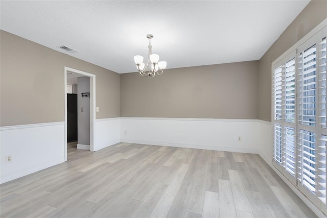 empty room featuring a chandelier and light hardwood / wood-style floors