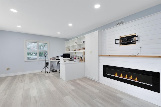 office with a large fireplace and light hardwood / wood-style flooring