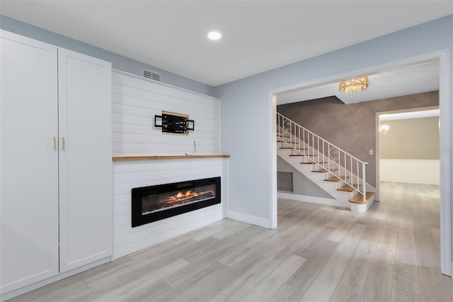 unfurnished living room featuring a large fireplace and light hardwood / wood-style flooring