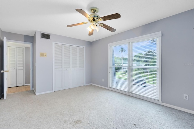 unfurnished bedroom with light colored carpet, ceiling fan, and a closet