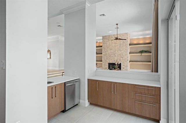 kitchen featuring light tile patterned flooring, a stone fireplace, ornamental molding, built in features, and stainless steel dishwasher