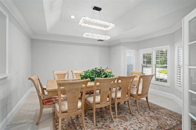 dining room with baseboards, a chandelier, a raised ceiling, and crown molding