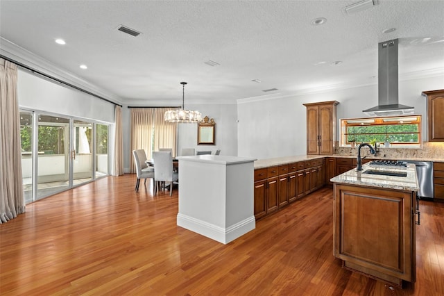 kitchen featuring decorative backsplash, a kitchen island, exhaust hood, a notable chandelier, and hardwood / wood-style flooring