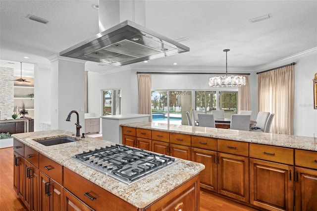 kitchen with light wood-type flooring, a kitchen island, stovetop, ventilation hood, and sink