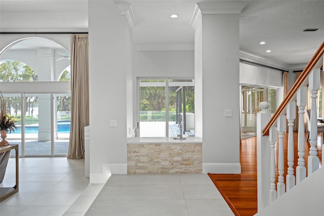 foyer with light wood-type flooring, ornamental molding, and a textured ceiling