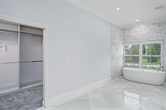 bathroom featuring crown molding, a bathing tub, tile patterned flooring, and tile walls