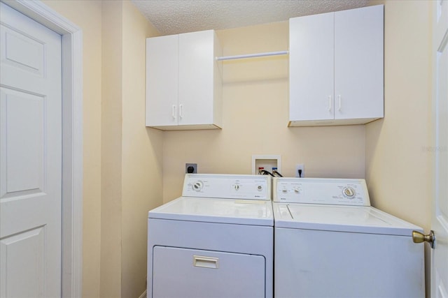 washroom with a textured ceiling, cabinets, and independent washer and dryer