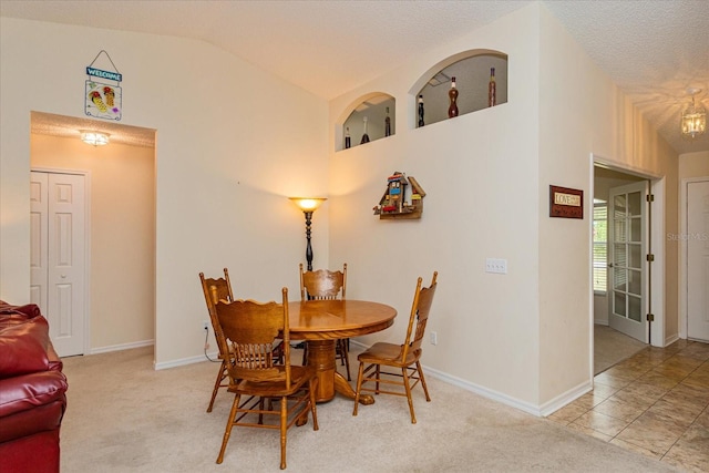 dining space with a textured ceiling, vaulted ceiling, and light tile patterned floors