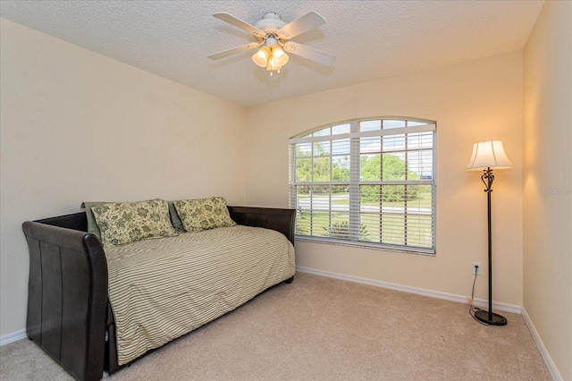 bedroom with a textured ceiling, ceiling fan, and light colored carpet