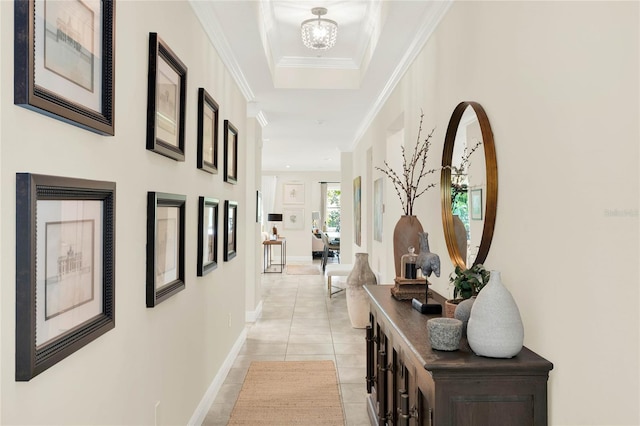 hall with light tile patterned floors, ornamental molding, an inviting chandelier, and baseboards