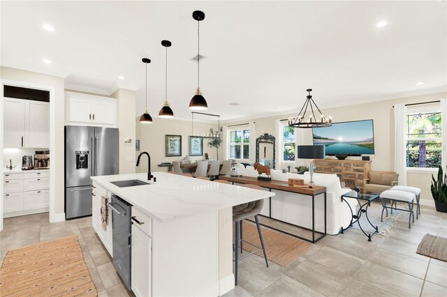 kitchen featuring appliances with stainless steel finishes, open floor plan, a center island with sink, and a sink