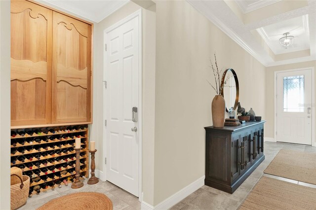 wine area featuring light tile patterned floors, a tray ceiling, ornamental molding, and baseboards