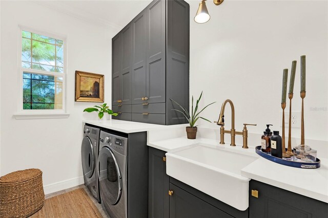 clothes washing area with separate washer and dryer, a sink, baseboards, cabinet space, and crown molding