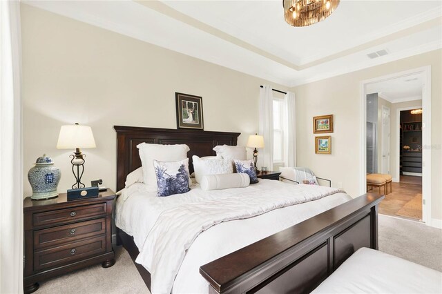 bedroom with visible vents, ornamental molding, a tray ceiling, and light colored carpet