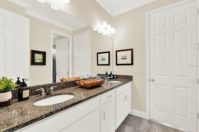 bathroom featuring double vanity, crown molding, baseboards, and a sink