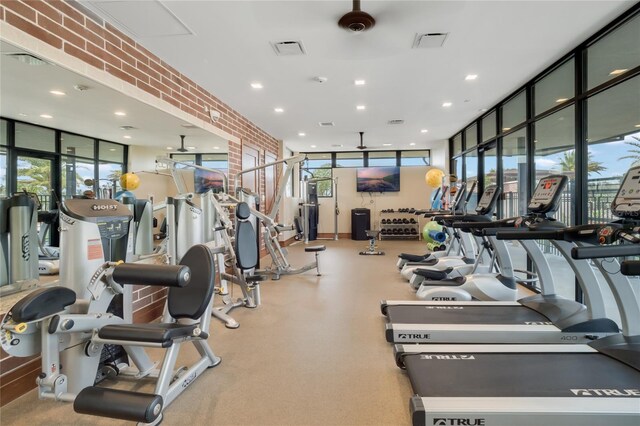 gym featuring a wall of windows, recessed lighting, visible vents, and brick wall