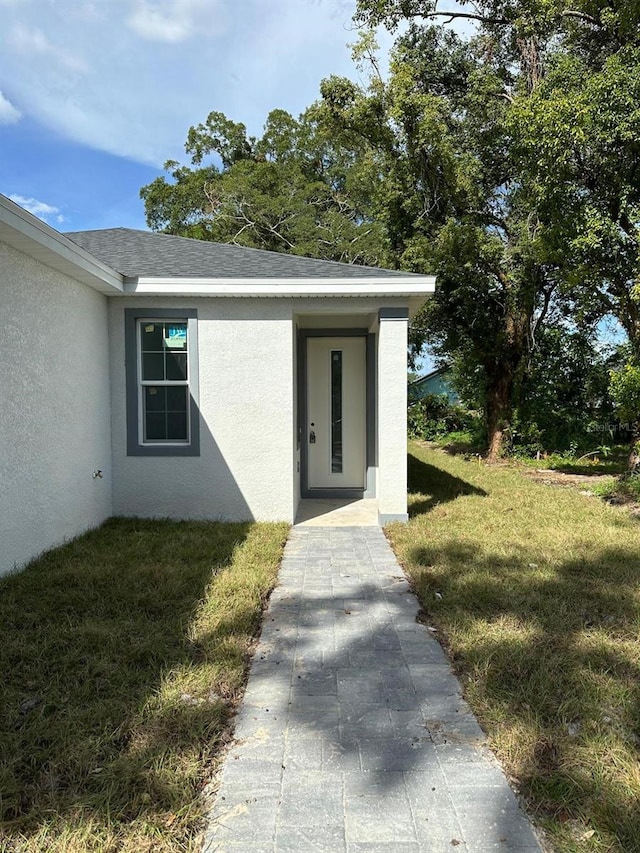 view of exterior entry featuring a lawn