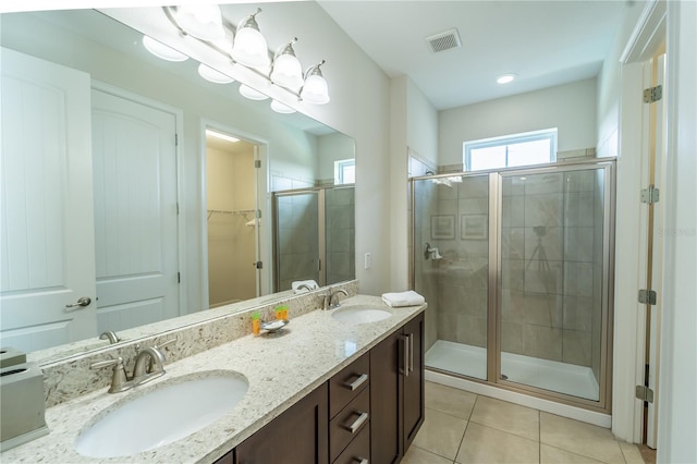 bathroom with a shower with shower door, vanity, and tile patterned floors