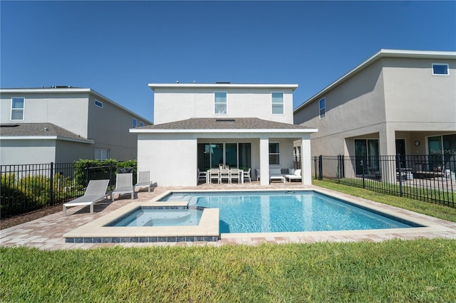 rear view of property featuring a swimming pool with hot tub, a patio, and a lawn