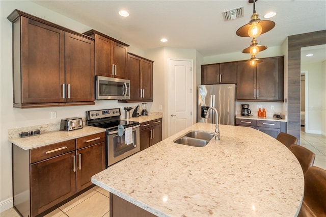 kitchen featuring appliances with stainless steel finishes, a breakfast bar, light tile patterned floors, and sink