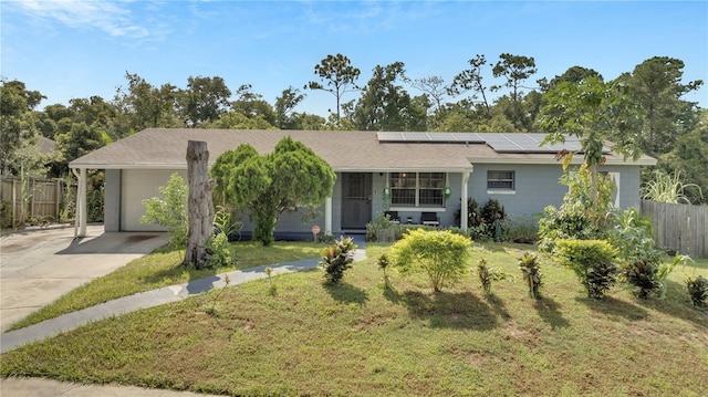 ranch-style home featuring a garage, solar panels, and a front lawn