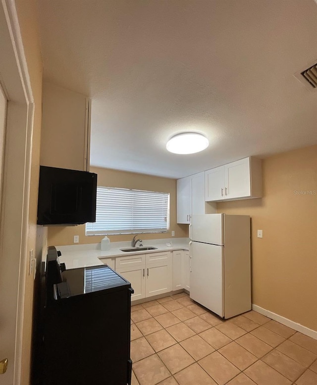 kitchen with white cabinetry, sink, white refrigerator, and light tile patterned floors