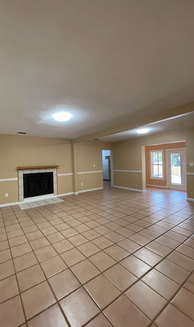 unfurnished living room with light tile patterned floors and a tile fireplace