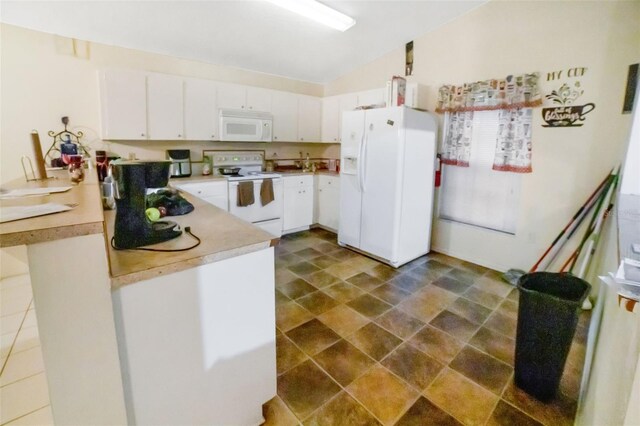 kitchen with dark tile patterned floors, white appliances, and white cabinets