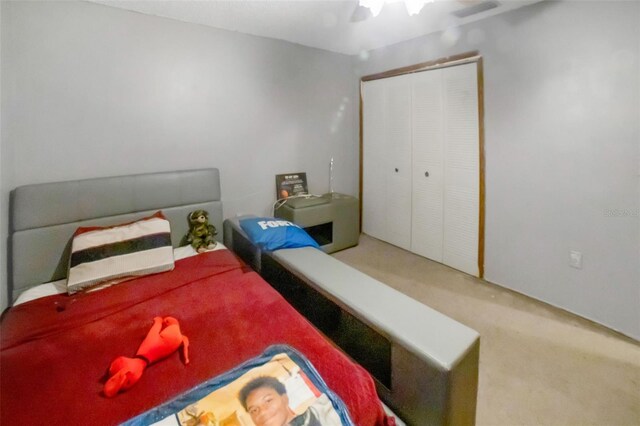 carpeted bedroom featuring a ceiling fan, a closet, and visible vents