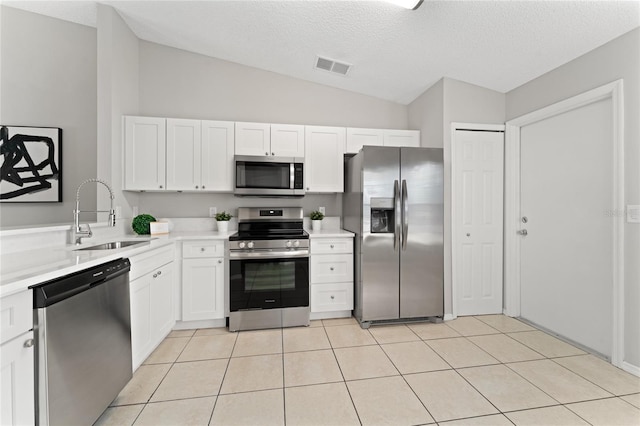 kitchen with appliances with stainless steel finishes, white cabinets, light countertops, and a sink