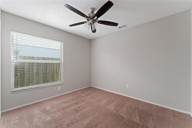 spare room featuring carpet floors, visible vents, and a textured ceiling