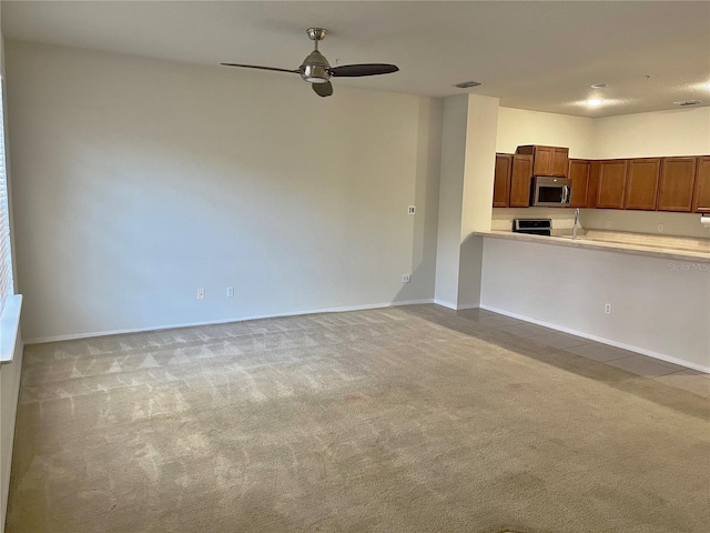 unfurnished living room featuring ceiling fan and light colored carpet