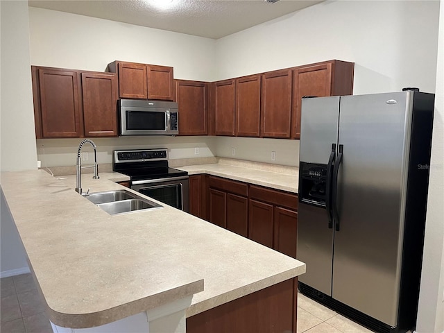 kitchen with kitchen peninsula, sink, light tile patterned floors, and stainless steel appliances