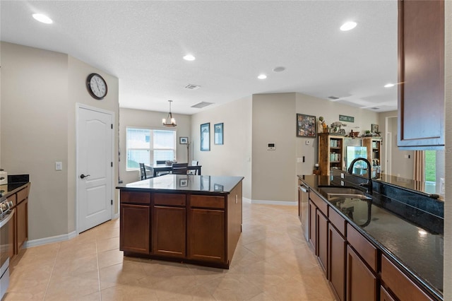 kitchen featuring appliances with stainless steel finishes, sink, a center island, pendant lighting, and a textured ceiling