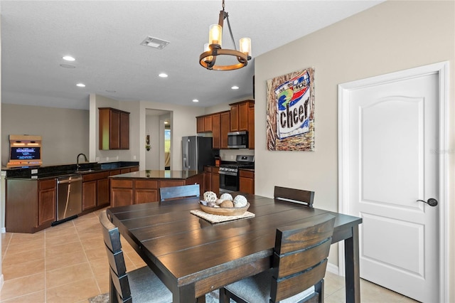 tiled dining space featuring sink, an inviting chandelier, and a textured ceiling