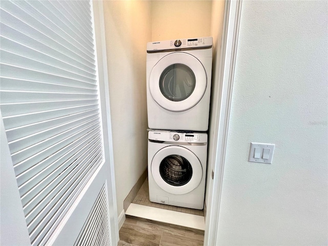 laundry area featuring wood-type flooring and stacked washing maching and dryer