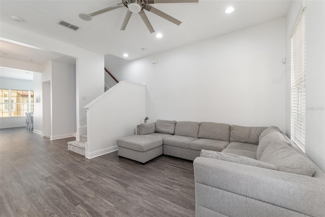 living area with dark wood-style flooring, visible vents, recessed lighting, and stairs